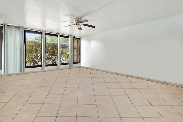 spare room with light tile patterned floors, ceiling fan, and a wall of windows