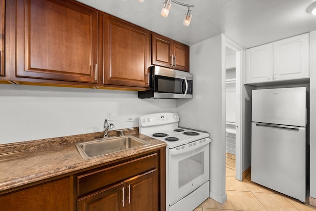 kitchen with stainless steel appliances, sink, light tile patterned floors, and track lighting