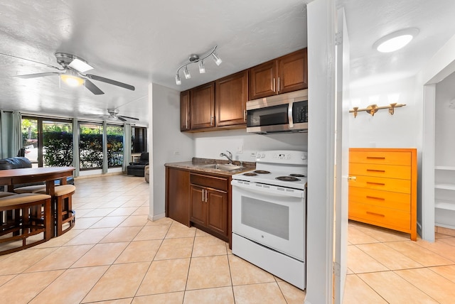 kitchen with a textured ceiling, light tile patterned floors, electric range, sink, and ceiling fan