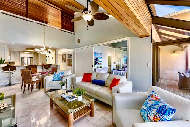 tiled living room with ceiling fan with notable chandelier and a towering ceiling