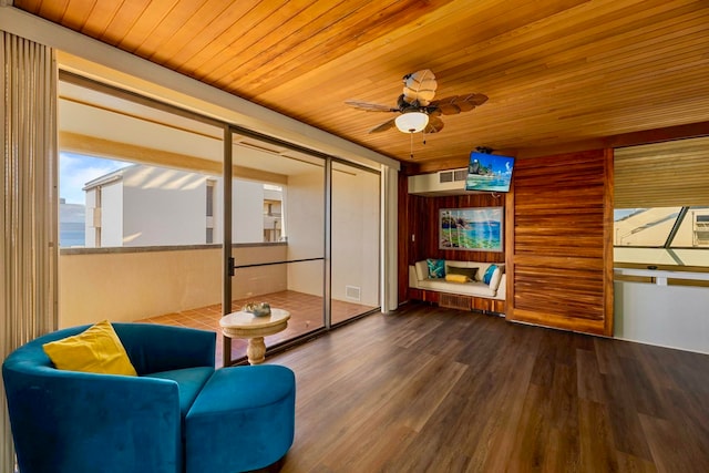 living area with wood-type flooring, ceiling fan, wooden ceiling, and wood walls