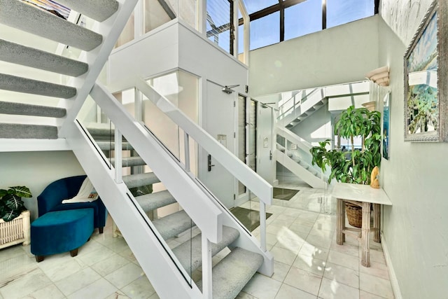 stairway with tile patterned flooring and a towering ceiling