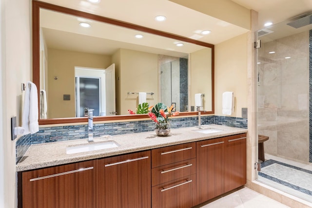 bathroom featuring a shower with door, vanity, tile patterned floors, and decorative backsplash