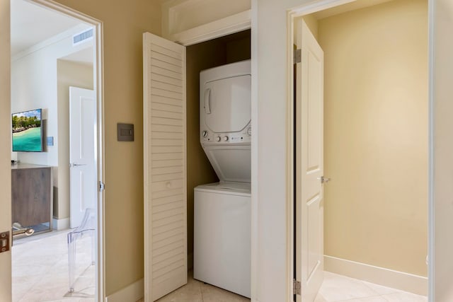 laundry room featuring light tile patterned flooring and stacked washer / drying machine