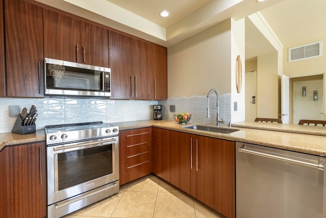 kitchen featuring light tile patterned flooring, tasteful backsplash, sink, kitchen peninsula, and stainless steel appliances