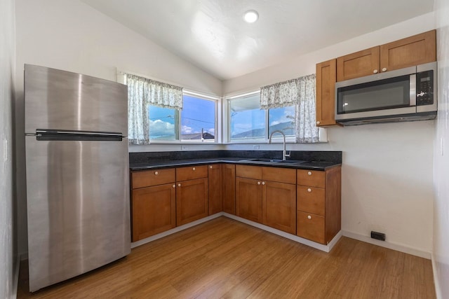 534 Kaikoo Pl, Wailuku, HI 96793 - kitchen with stainless steel appliances, a sink, light wood finished floors, brown cabinetry, and lofted ceiling