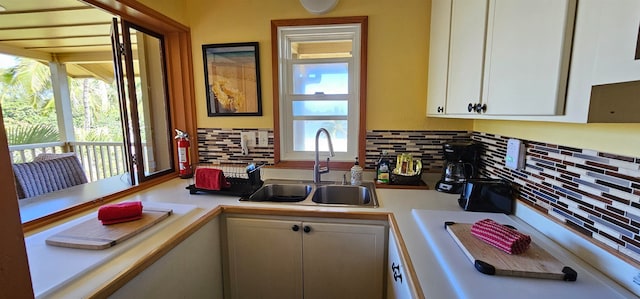 kitchen featuring a healthy amount of sunlight, decorative backsplash, white cabinetry, and sink