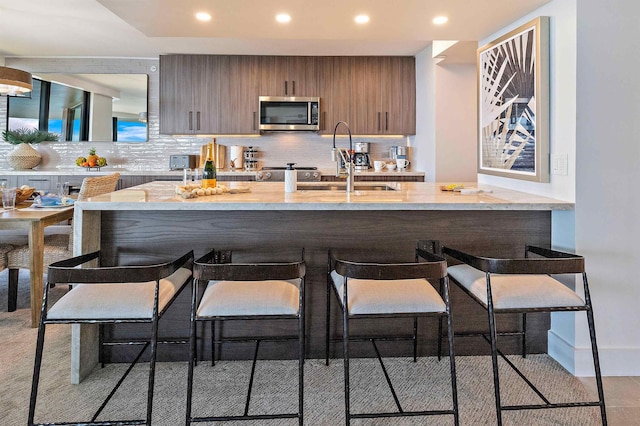 kitchen featuring light tile patterned flooring, a kitchen breakfast bar, kitchen peninsula, and tasteful backsplash