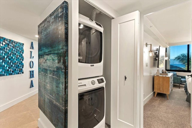 clothes washing area featuring light tile patterned floors and stacked washer / dryer