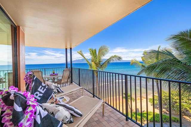 balcony with a water view and a view of the beach