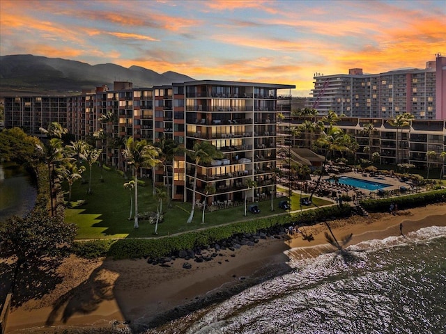 outdoor building at dusk with a water and mountain view and a view of the beach