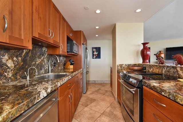 kitchen with sink, light tile patterned floors, appliances with stainless steel finishes, decorative backsplash, and dark stone counters