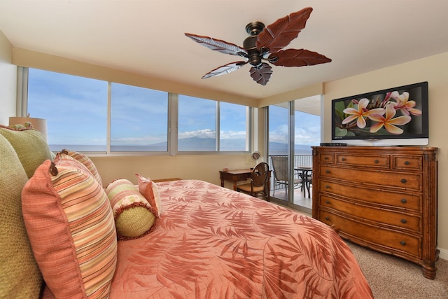 bedroom featuring multiple windows, a water view, carpet flooring, and ceiling fan