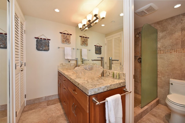 bathroom featuring vanity, toilet, and a tile shower