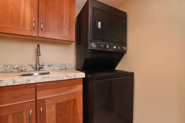 washroom featuring cabinets, stacked washer / drying machine, and sink