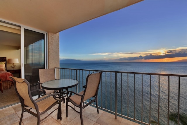 balcony at dusk with a water view and a beach view