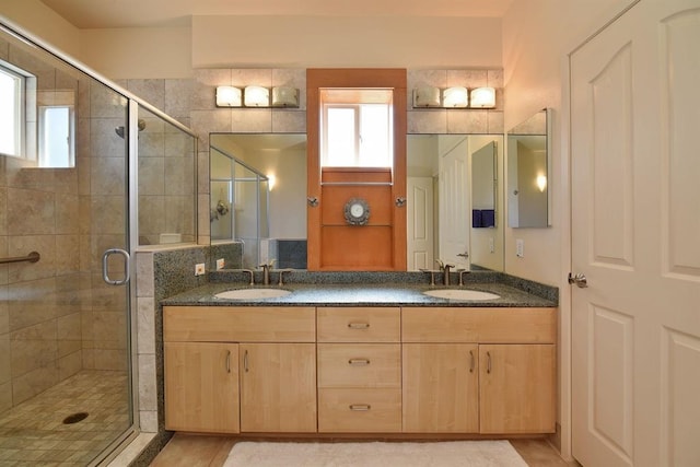 bathroom with a stall shower, a sink, and double vanity