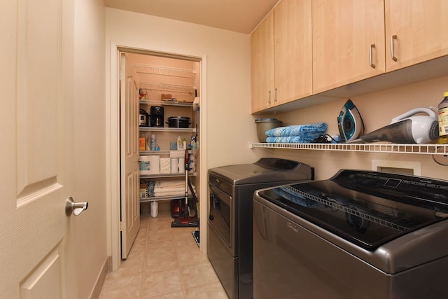 washroom featuring cabinet space, washing machine and clothes dryer, and light tile patterned flooring