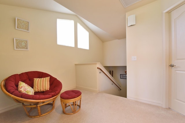 living area with lofted ceiling, visible vents, light colored carpet, and an upstairs landing