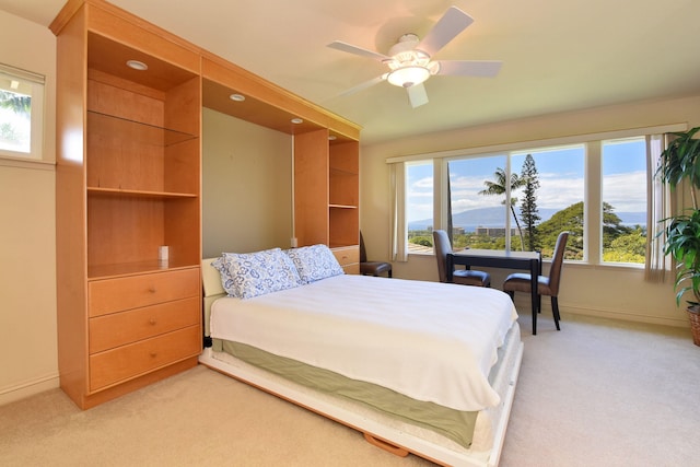 bedroom with light carpet, a mountain view, baseboards, and ceiling fan