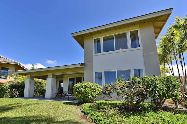 rear view of house featuring a patio area and a yard