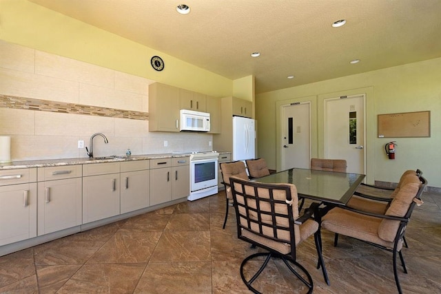 kitchen featuring white appliances, decorative backsplash, light countertops, a sink, and recessed lighting