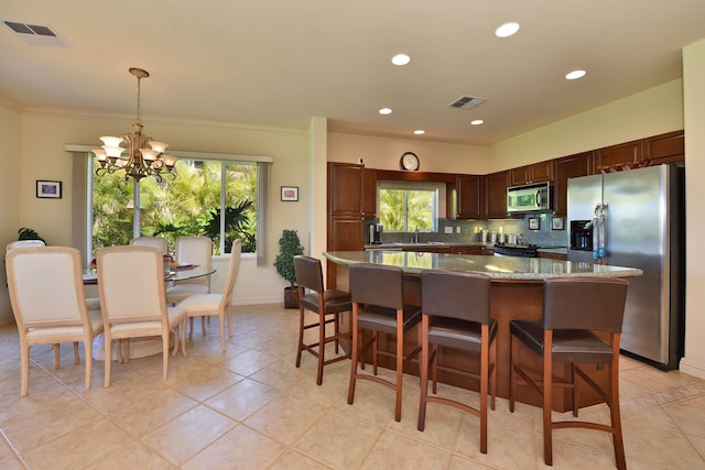 kitchen with appliances with stainless steel finishes, visible vents, decorative light fixtures, and tasteful backsplash