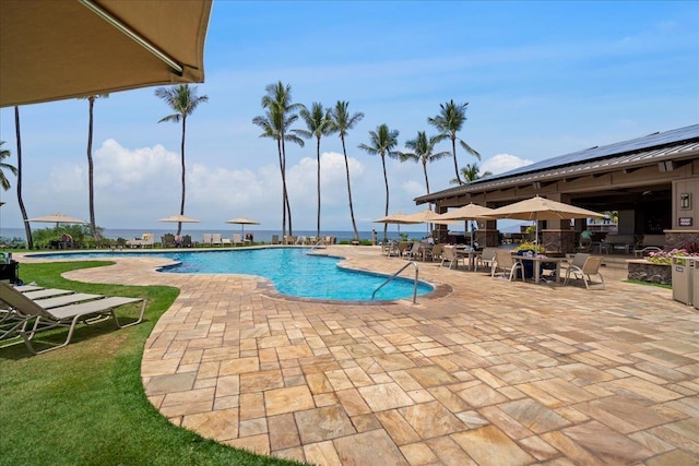 community pool with a patio and outdoor dining space