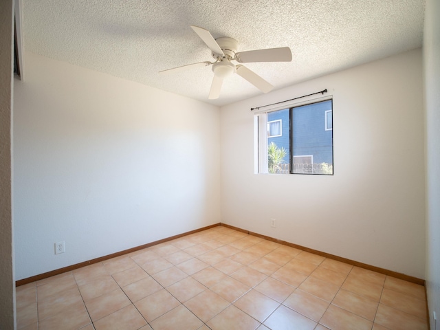 empty room with ceiling fan, light tile patterned flooring, and a textured ceiling