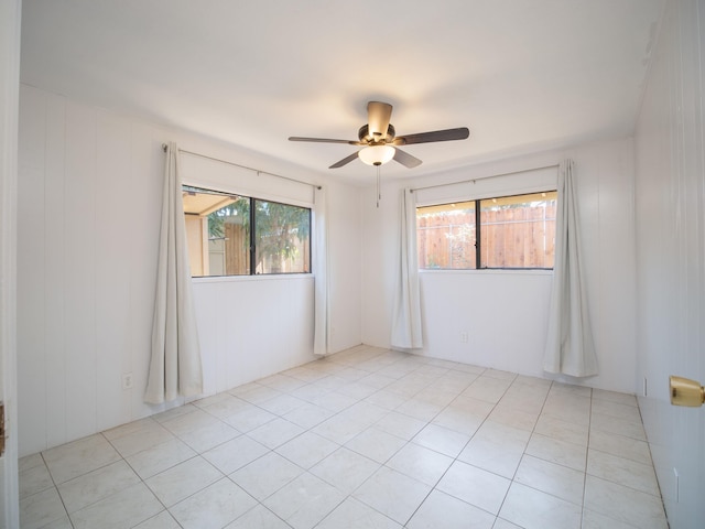 empty room with ceiling fan and light tile patterned floors