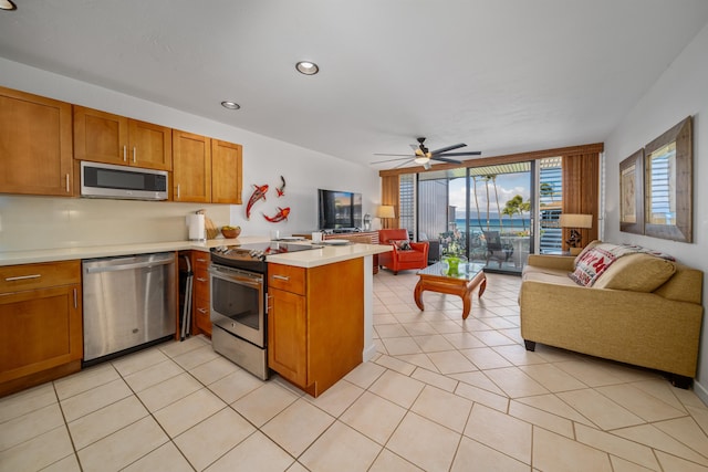 kitchen with floor to ceiling windows, light tile patterned floors, kitchen peninsula, ceiling fan, and appliances with stainless steel finishes