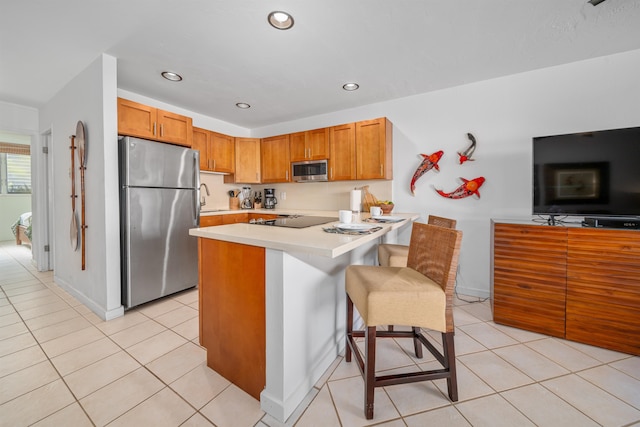 kitchen with light tile patterned flooring, sink, a kitchen bar, appliances with stainless steel finishes, and kitchen peninsula