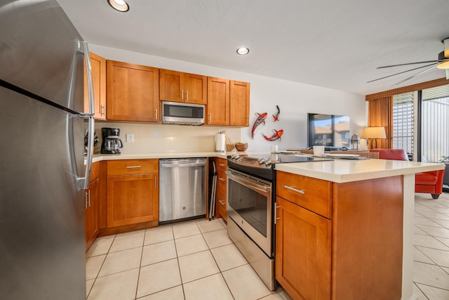 kitchen featuring light tile patterned flooring, kitchen peninsula, appliances with stainless steel finishes, and ceiling fan