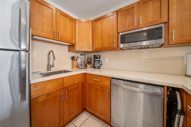 kitchen with light tile patterned flooring, appliances with stainless steel finishes, and sink