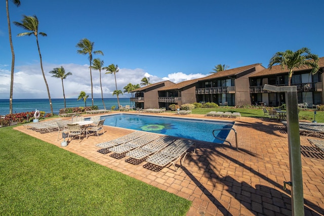 view of swimming pool with a patio area, a water view, and a yard