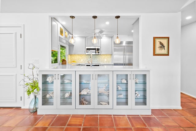 bar with ceiling fan, appliances with stainless steel finishes, backsplash, tile flooring, and decorative light fixtures