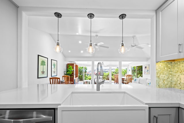 kitchen featuring vaulted ceiling, ceiling fan, backsplash, hanging light fixtures, and sink