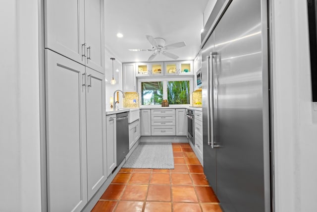 kitchen featuring stainless steel appliances, light tile flooring, ceiling fan, backsplash, and hanging light fixtures