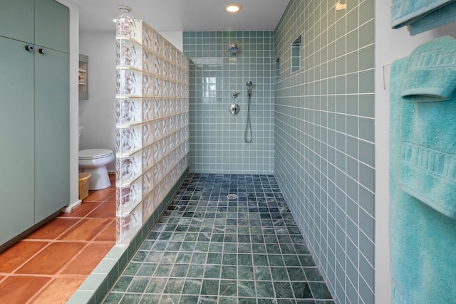 bathroom with tile floors, toilet, and tiled shower