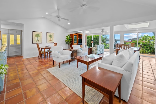 living room with lofted ceiling with skylight, light tile floors, and ceiling fan