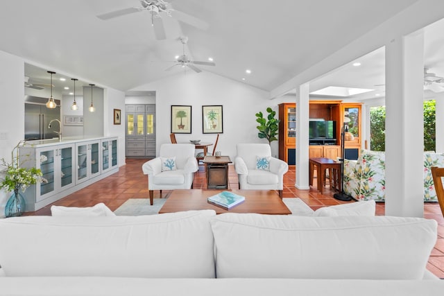 tiled living room with ceiling fan, sink, and vaulted ceiling