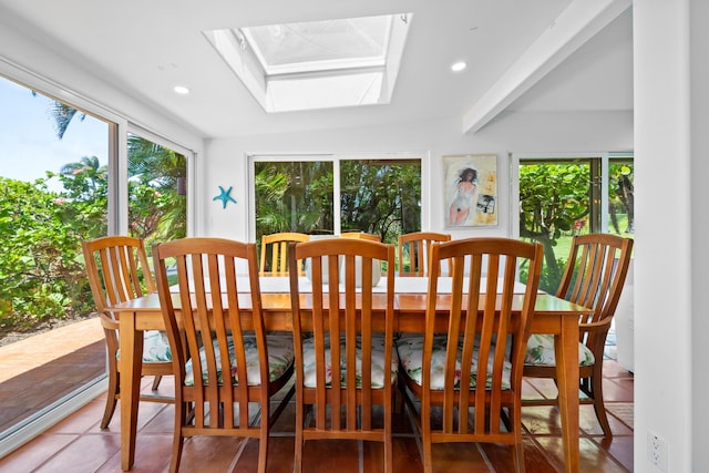 tiled dining room featuring vaulted ceiling with skylight