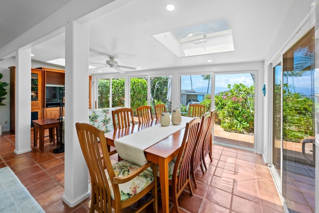 sunroom / solarium featuring a skylight, a tray ceiling, ceiling fan, and a wealth of natural light