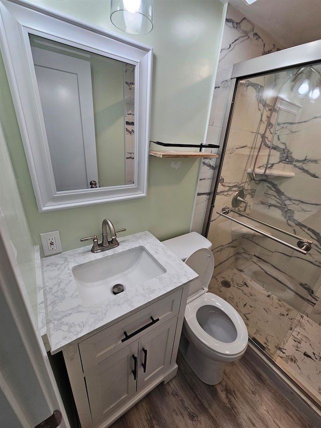 bathroom featuring wood-type flooring, vanity, a shower with door, and toilet