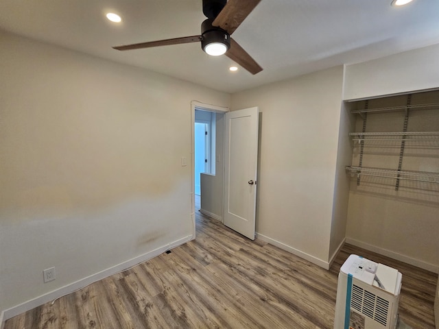 unfurnished bedroom featuring hardwood / wood-style floors, ceiling fan, and a closet