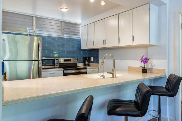 kitchen with a breakfast bar, appliances with stainless steel finishes, white cabinetry, and sink