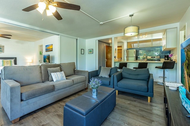 living room featuring hardwood / wood-style flooring, ceiling fan, sink, and a textured ceiling