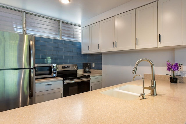 kitchen with decorative backsplash, white cabinetry, sink, and appliances with stainless steel finishes