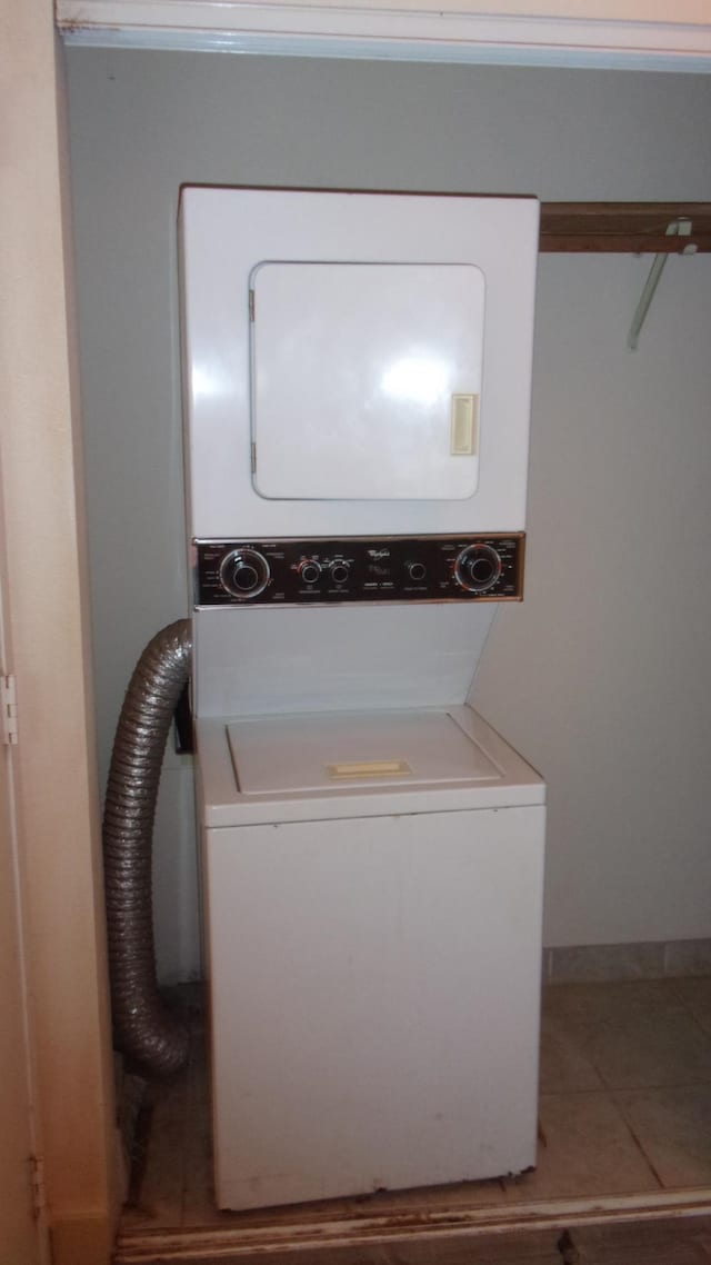 clothes washing area with light tile patterned floors and stacked washer / dryer