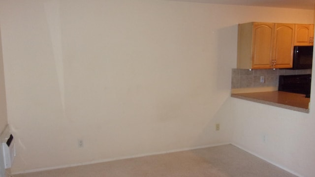 interior space featuring tasteful backsplash, light brown cabinetry, and carpet